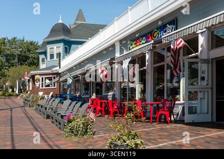 Farbenfrohes Straßencafé mit roten Stühlen, Fahnen und Geschäften in Old Orchard Beach, Maine, USA Stockfoto