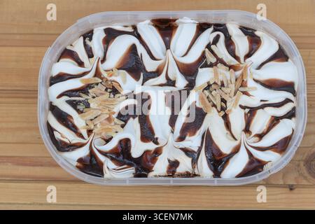 Geschwenkte Vanille- und Schokoladeneis mit Mandelsplittern auf rustikaler Holzoberfläche. Stockfoto
