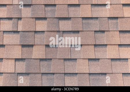 Nahaufnahme von Asphaltschindeln auf Wohndach mit strukturiertem Muster in Braun und Grau. Stockfoto
