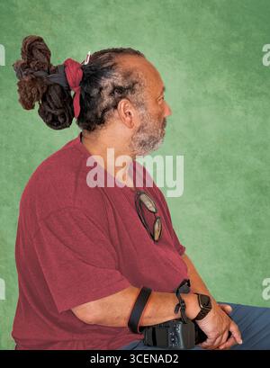 New York City – 18. Juni 2025: Porträt eines dunkelhäutigen Mannes mit lockiger ungewöhnlicher Afro-Frisur, isoliert über grünem Hintergrund Stockfoto