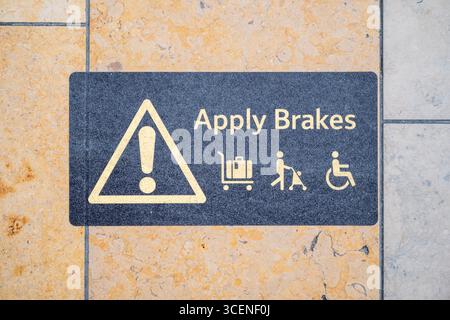 Betätigen Sie die Bremsen, und warnen Sie Passagiere mit Kinderwagen, Rollstühlen und Gepäckwagen an einer Wand an einem Bahnhof in London Stockfoto