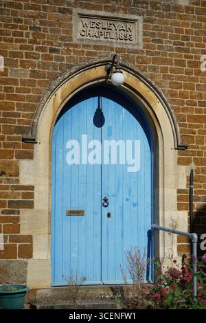 Historische blaue Kirchentür mit Ziegelwerk und gravierter Tafel. Adderbury, England Stockfoto