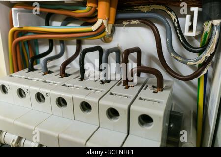 Nahaufnahme von elektrischen Kabeln, die mit einer Schutzschalttafel verbunden sind. Stockfoto
