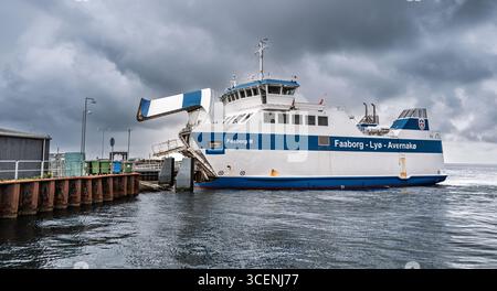 Eine Fähre namens „Faaborg III“, die an einem bewölkten Tag an einem Hafenterminal stationiert ist und ihre offene Rampe für Passagiere oder Fahrzeuge zeigt. Der Backg Stockfoto
