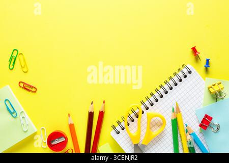 Schulzubehör, Buntstifte, Notizbuch auf gelbem Tisch. Back-to-School-Konzept. Flache Lagen. Stockfoto