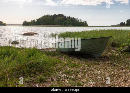 Fantastischer goldener Sonnenuntergang von der Insel Ruissalo über dem Turku-Archipel im Südosten Finnlands mit Blick auf ein kleines Boot, das häufig auf dem benutzt wird Stockfoto