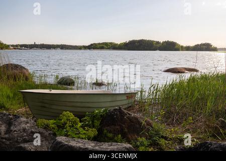 Fantastischer goldener Sonnenuntergang von der Insel Ruissalo über dem Turku-Archipel im Südosten Finnlands mit Blick auf ein kleines Boot, das häufig auf dem benutzt wird Stockfoto