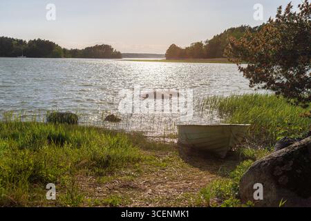 Fantastischer goldener Sonnenuntergang von der Insel Ruissalo über dem Turku-Archipel im Südosten Finnlands mit Blick auf ein kleines Boot, das häufig auf dem benutzt wird Stockfoto
