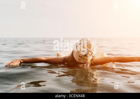 Frau Sea Float entspannender Sommer - Eine Frau entspannt sich auf einem Schwimmer im Meer an einem sonnigen Tag. Stockfoto