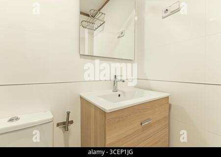 Modernes Badezimmer mit einem an der Wand montierten Kosmetikbereich aus alter Eiche und zwei Schubladen, die Charakter und Zweckmäßigkeit auf kleinem Raum kombinieren Stockfoto