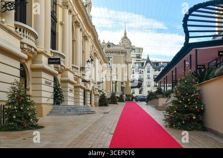 Allee Francois Blanc, Straße vor dem Monte Carlo Casino (links), dekoriert mit einem roten Teppich und Weihnachtsbäumen im Winter, Monaco Stockfoto