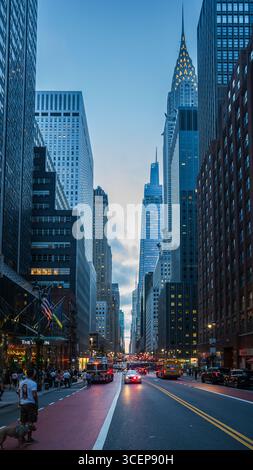 New York, Vereinigte Staaten - 11. Juli 2025: Blick auf das Chrysler Building, das durch die Skyline ragt, eingerahmt von den hohen Gebäuden und belebten Straßen darunter. Stockfoto