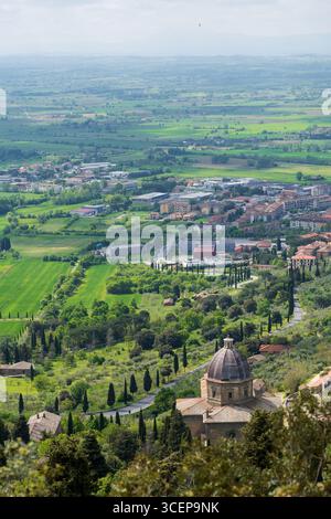 Montepulciano, Toskana, Italien - 24. April 2025: Blick auf die Stadt im grünen Tal, mit der Kuppel der Kirche, die unter dem sanften toskanischen Sonnenlicht leuchtet. Stockfoto