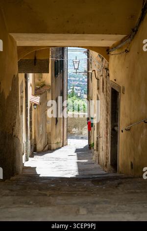 Cortona, Toskana, Italien - 24. April 2025: Blick auf die alte Steinallee mit ihren warmen Erdtönen, die einen weiten blick auf grüne Hügel und Dächer bilden. Stockfoto