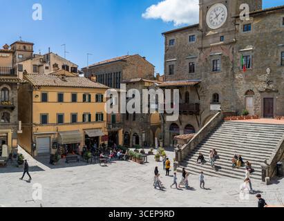 Cortona, Toskana, Italien - 24. April 2025: Blick auf die Piazza Della Repubblica, wo alte Steinbauten auf den azurblauen Himmel treffen und die große Treppe die Besucher begrüßt. Stockfoto