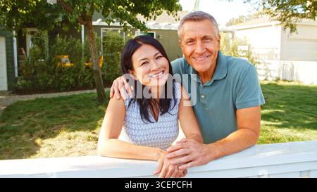 Porträt Eines Lächelnden Älteren Ehepaares Zu Hause, Der Über Den Hinterhof-Zaun Blickt Stockfoto