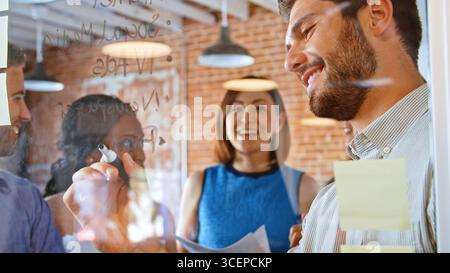 Geschäftsmann schreiben Ideen auf Glasscheibe während der Sitzung Stockfoto
