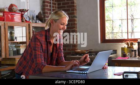 Seitenansicht Einer Jungen Frau Mit Laptop In Der Offenen Wohnküche Stockfoto