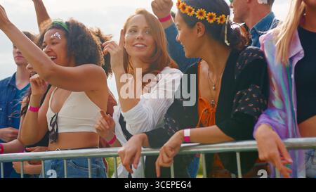 Junge Freunde im Publikum hinter Schranke Tanzen und Singen bei Outdoor Festival Musik genießen Stockfoto