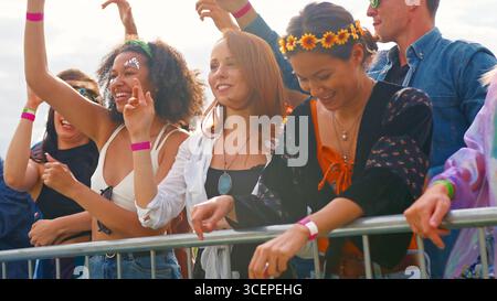 Junge Freunde im Publikum hinter Schranke Tanzen und Singen bei Outdoor Festival Musik genießen Stockfoto