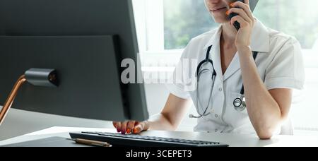 Ärztliche Beratung, Krankenhaus-Helpdesk. Der Arzt arbeitet am Computer und spricht am Telefon in der Klinik. Kopierbereich Stockfoto