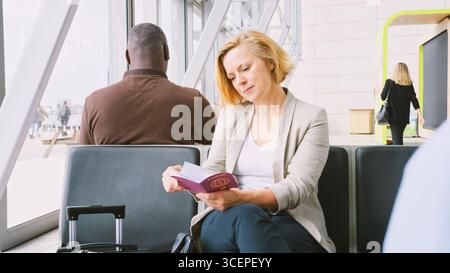 Reife Geschäftsfrau, Die In Der Airport Departure Lounge Sitzt Und Tickets Und Reisepässe Überprüft Stockfoto