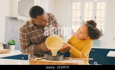 Familienfoto Mit Vater Und Tochter Backen Zu Hause In Der Küche, Kuchenmischung In Die Dose Gießen Stockfoto