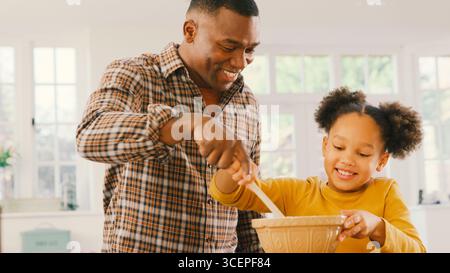 Familienfoto Mit Vater Und Tochter Backen Zu Hause In Der Küche, Mixen Von Zutaten In Der Schüssel Stockfoto
