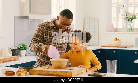 Familienfoto Mit Vater Und Tochter Backen Zu Hause In Der Küche, Mixen Von Zutaten In Der Schüssel Stockfoto
