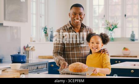 Porträt Von Stolzen Vater Und Tochter In Home In Kitchen Mit Hausgemachtem Kuchen, Den Sie Zusammen Gebacken Haben Stockfoto