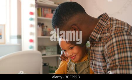 Liebevoller Vater umarmt die Tochter zu Hause im Mädchenschlafzimmer Stockfoto