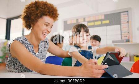 Lehrer mit weiblicher Grundschulschülerin mit digitalem Tablet in der MINT-Klasse Stockfoto