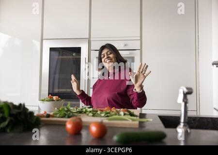 Lächelnde ältere Frau, die sich appetitliches Gemüse ansieht, das für Salat geschnitten wurde Stockfoto