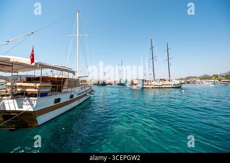 Kas, Antalya, Türkei - 9. Juli 2025: Farbenfrohe Ausflugsboote legen am belebten Hafen von Kas in Antalya an Stockfoto