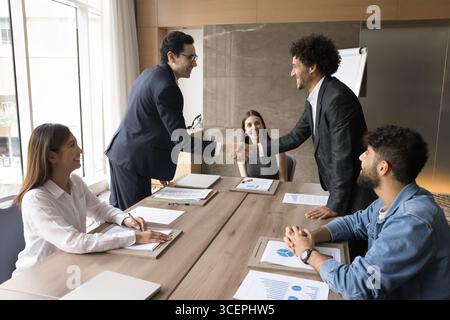 Zwei junge Männer, die bei der Direktorenversammlung Hand schütteln Stockfoto