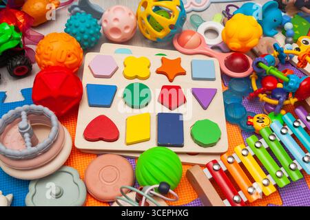 Ein Haufen verschiedener Kinderspielzeuge, verstreut auf einer Spielmatte. Stockfoto