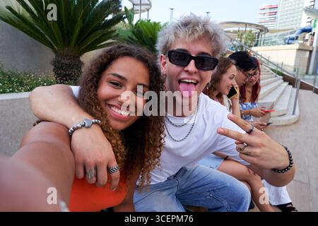 Zwei Freunde machen zusammen ein lustiges Selfie, während sie sich draußen treffen und fröhlich in die Kamera schauen. Stockfoto