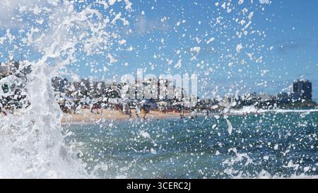 Spritzer einer Strandwelle, die hart gegen einen Zementpfeiler kracht. Wintersaison. Kraft der Natur. Stockfoto