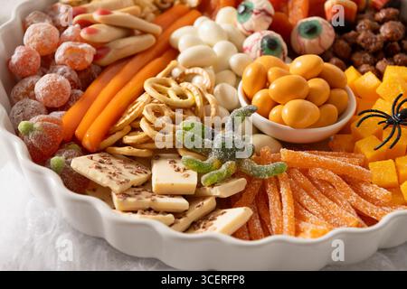 Halloween Charcuterie Board mit Schokoladenbonbons, Spinne, Cracker auf weißem Hintergrund. Festliches Essen für Kinder Party. Nahaufnahme. Stockfoto