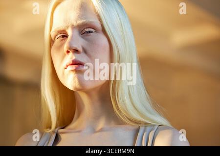 Horizontales Nahporträt einer jungen kaukasischen Frau mit Albinismus, die bei Tageslicht steht und wegblickt Stockfoto