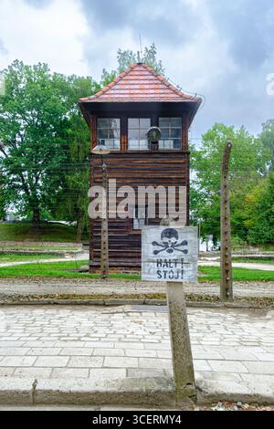 Eine Nahaufnahme eines Wachturms in Auschwitz I mit einem Halt! Stoj!“ Warnschild, ein erschreckendes Symbol für die tödliche Kontrolle und Autorität des Lagers. Stockfoto