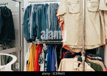 Farbenfrohe Kleidung hängt an Regalen in einem Second-Hand-Geschäft in Budapest und bietet eine lebendige Mischung aus Second-Hand-Mode und einzigartigen Stilen Stockfoto