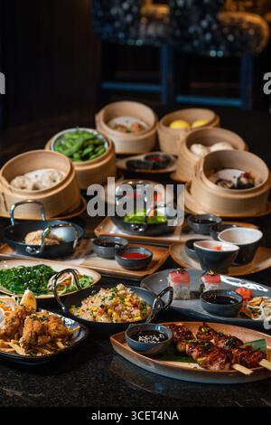 Auswahl chinesischer Speisen. Chinesische Nudeln, gebratener Reis, Knödel, Dim Sum, Frühlingsrollen. Berühmte chinesische Gerichte auf schwarzem Hintergrund Stockfoto