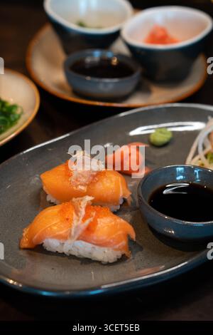 Frisches Nigiri-Sushi, serviert auf einem Teller mit Sojasauce und Gemüse Stockfoto