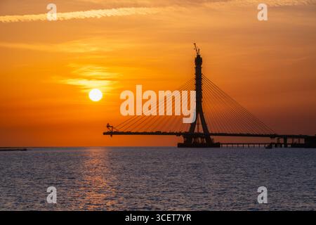 Wunderschöner Sonnenuntergang mit rosa und orangen Himmeln über der Danshui Tamsui Brücke im Bau in Taiwan, mit ruhigen Wellen. Erschossen am 29. April 2025. Stockfoto