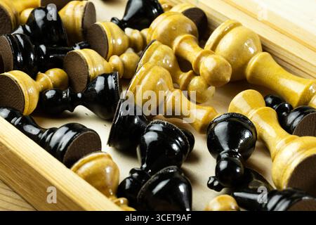 Eine Sammlung von schwarz-weißen Schachfiguren, verstreut in einer Holzkiste. Stockfoto