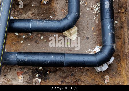 Neue moderne, isolierte städtische Rohrleitungsbaustelle freiliegende unterirdische Rohre in Unterwassergräben. Isolierte Stahlrohre liegen an Stockfoto