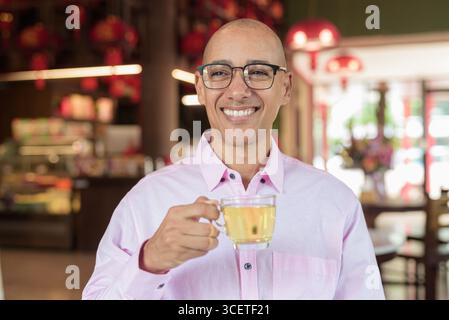 Glatze Hispanic reifer Mann in den 40er Jahren mit rosa lässigem Business-Shirt und Brille im chinesischen Teehaus-Restaurant. Kulturbegriff Relaxati Stockfoto