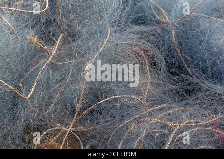 Ein Nahbild, das verworrene Fischernetze mit feinen Fasern und Seilen zeigt, die komplizierte Muster und Texturen im maritimen Kontext hervorheben. Stockfoto