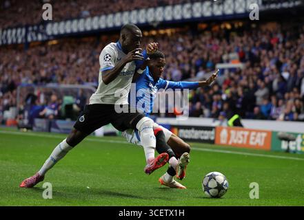 Rangers Jayden Meghoma und Club Brugge Carlos scheitern um den Ball während der UEFA Champions League, Play-off, im ersten Legspiel im Ibrox Stadium, Glasgow. Bilddatum: Dienstag, 19. August 2025. Stockfoto